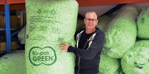 Een zak groene, milieuvriendelijke opvulchips wordt vast gehouden